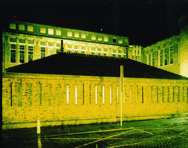 108469 Gezicht op de achtergevel van het hoofdpostkantoor (Neude 11) te Utrecht, vanaf de Oudegracht, bij avond.